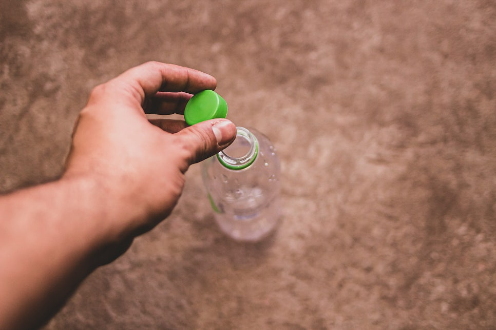 페트병 뚜껑을 열고 닫는 손의 클로즈업 | 출처: Unsplash